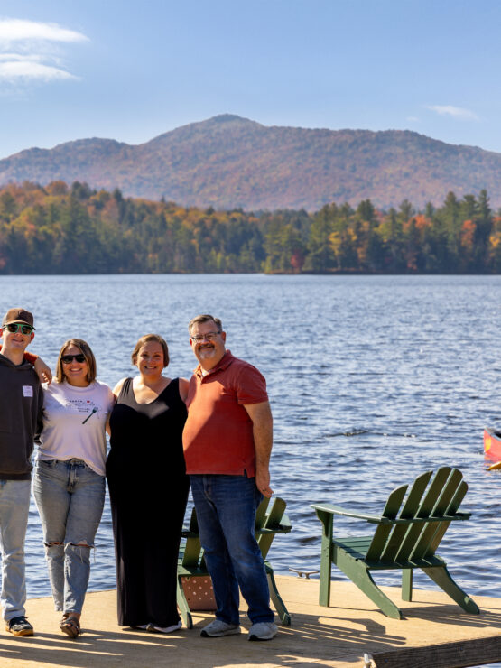 Five people standing on a dock with a canoe in the background