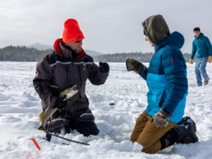 Two people kneeling on ice and fist bumping